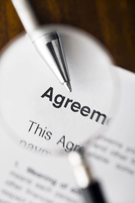 magnifying glass over agreement paperwork and pen